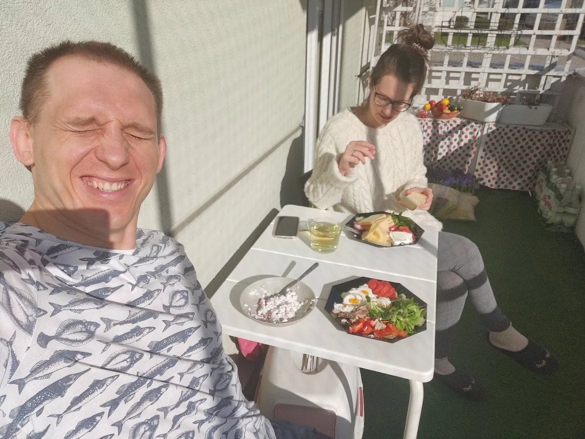 People sit around a table and eat. The man smiles.
